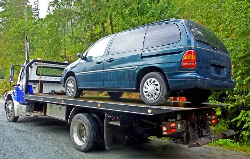 blue tow truck with the loaded old damaged car which stopped